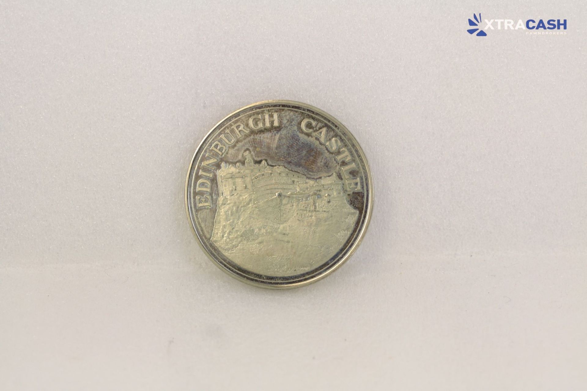 Silver coin with a dark winged emblem on a light background
