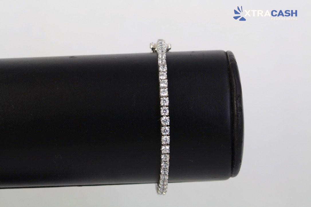 Silver tennis bracelet on a black display stand
