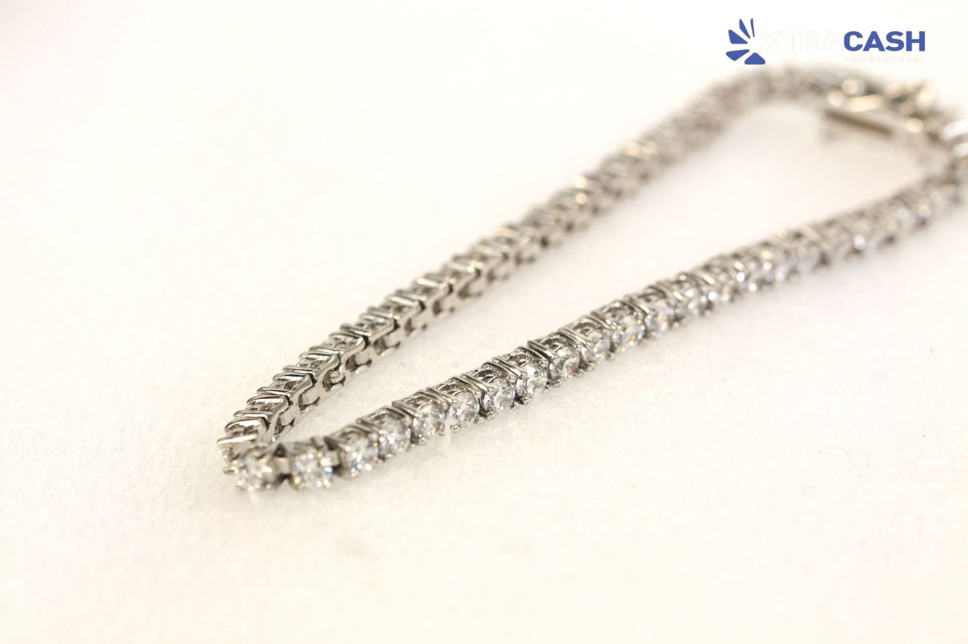 Silver tennis bracelet on a black display stand