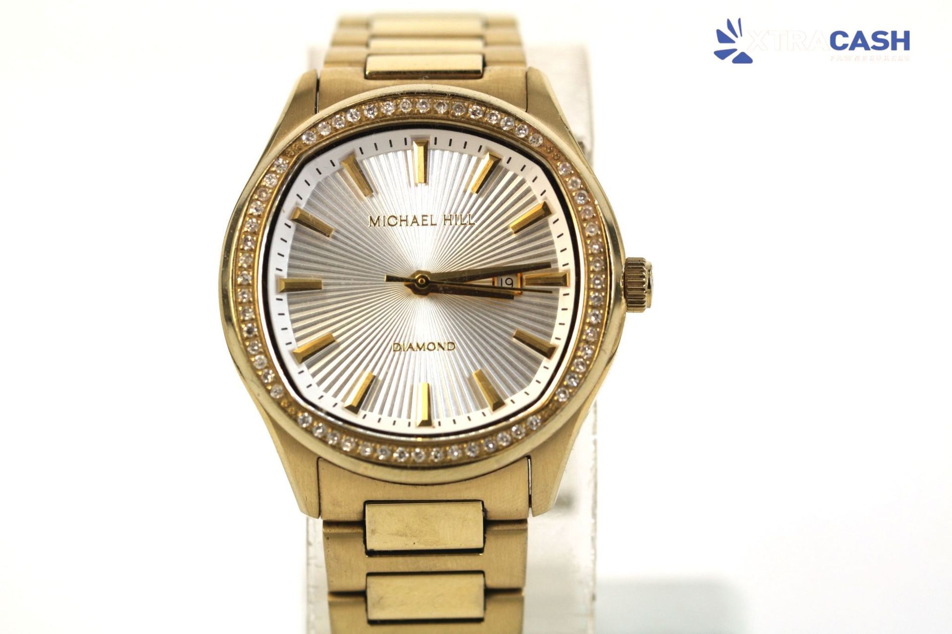 Gold wristwatch with a silver dial and jeweled bezel on a bracelet band