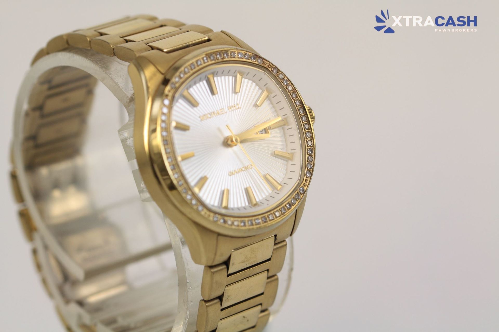 Gold wristwatch with a silver dial and jeweled bezel on a bracelet band