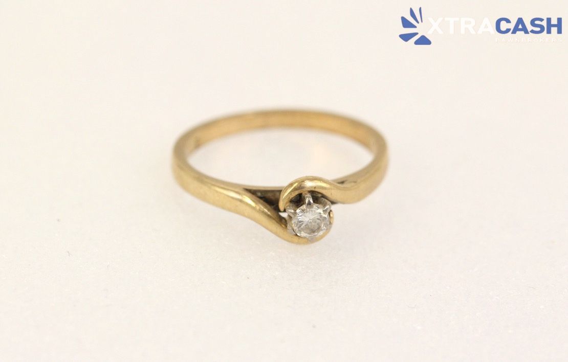 Gold ring with a small clear gemstone on a white background