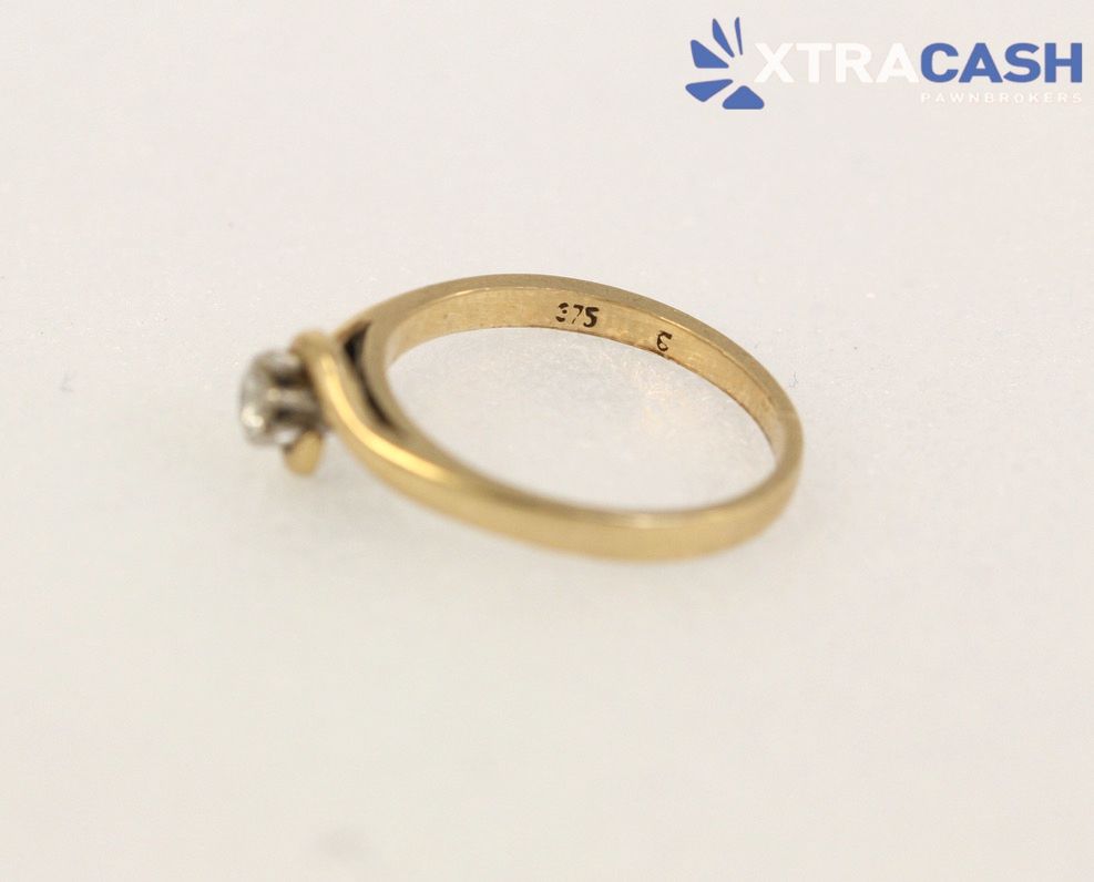 Gold ring with a small clear gemstone on a white background