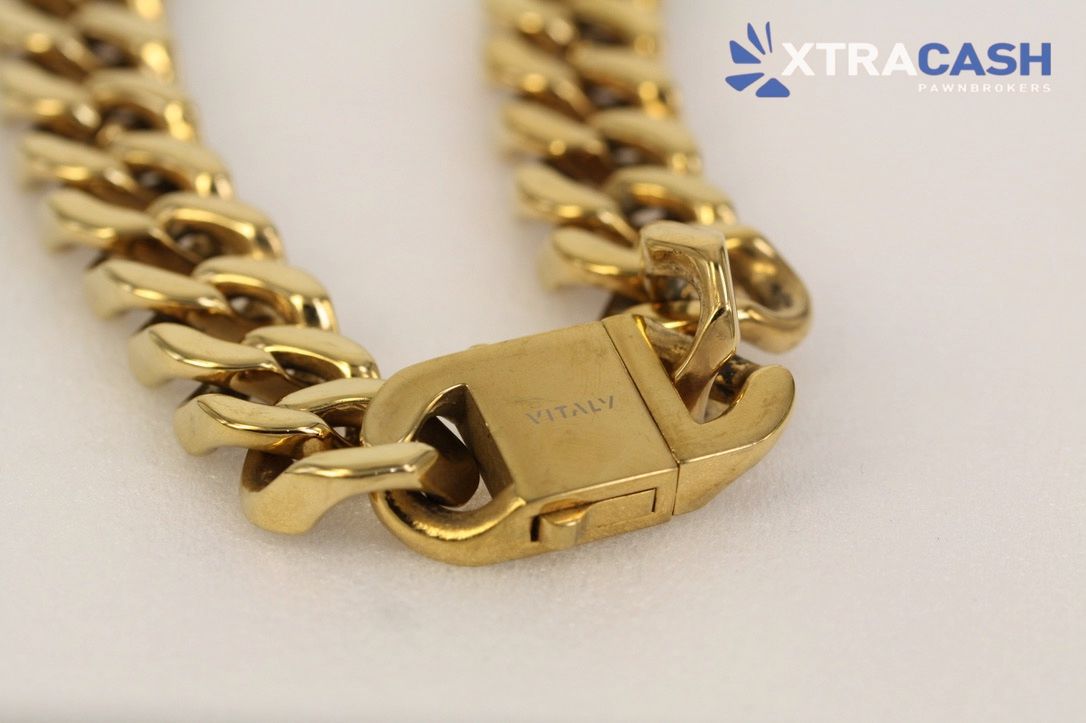 Gold Cuban link chain on a black display stand with XTRACASH logo.