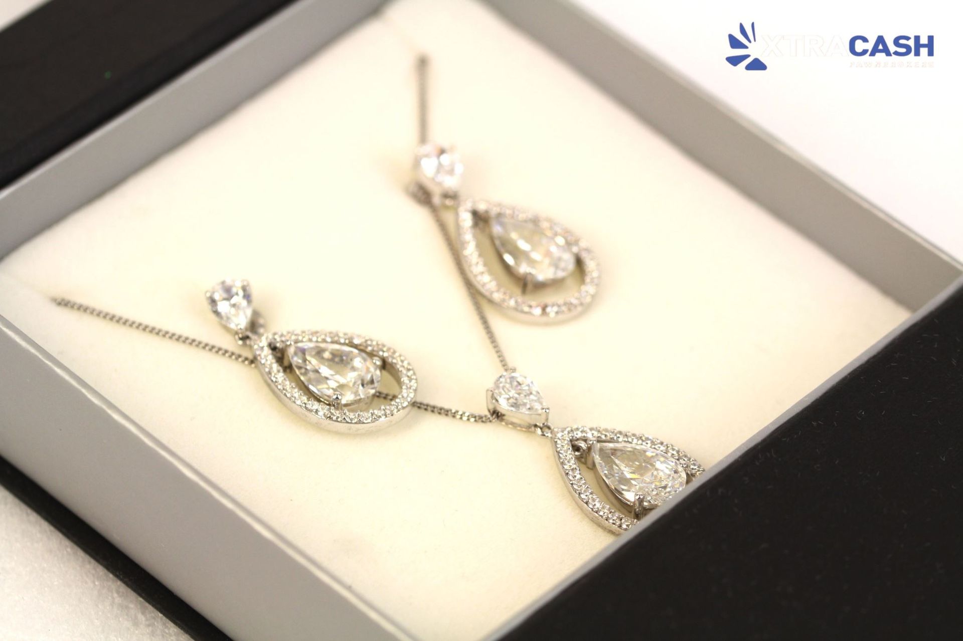 Silver teardrop necklace and earrings set displayed in a black jewelry box