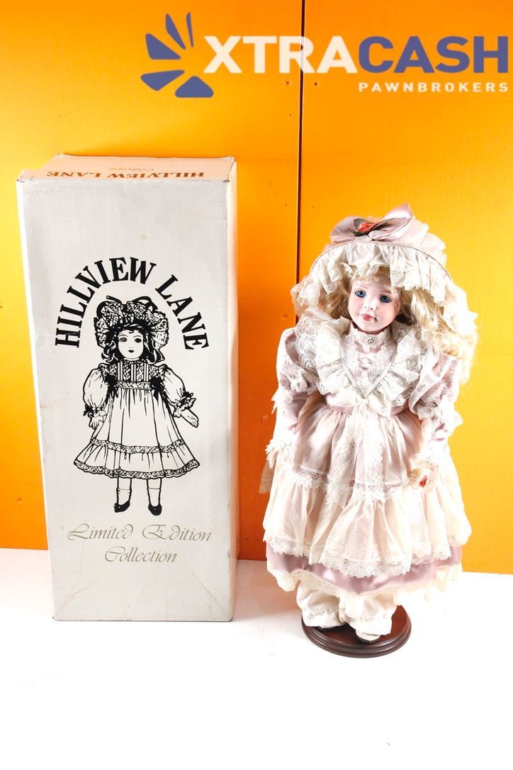 Antique doll beside Hillview Lane box in front of orange XtraCash Pawn Brokers sign