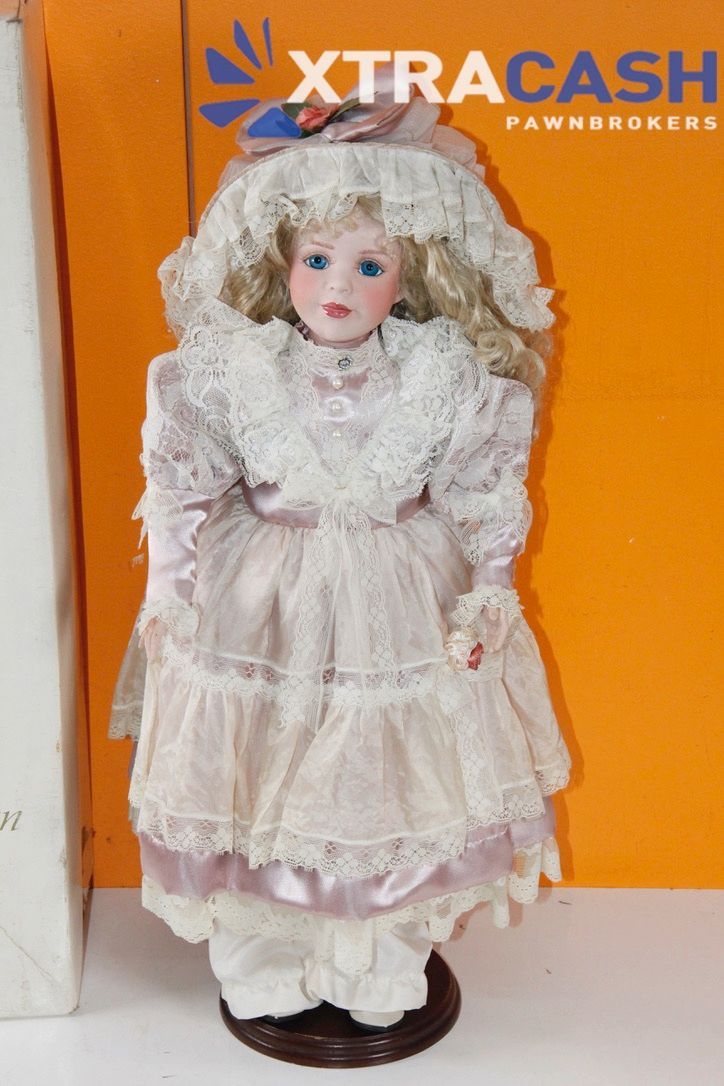 Antique doll beside Hillview Lane box in front of orange XtraCash Pawn Brokers sign