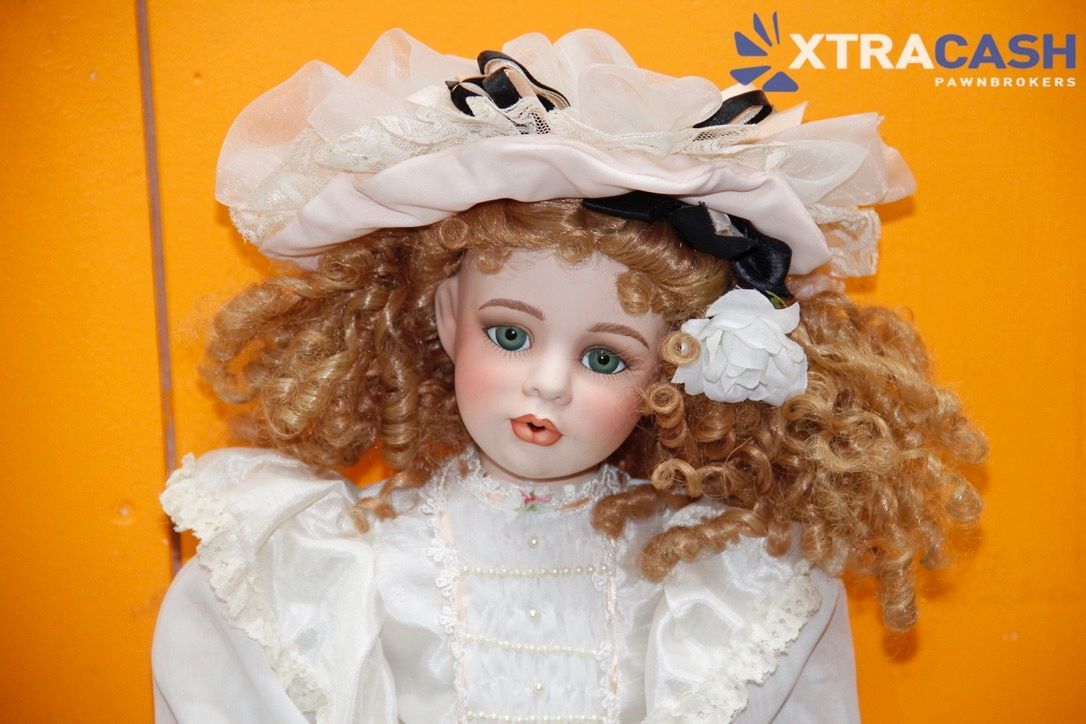 Vintage doll beside Halloween-themed box on orange and white display background