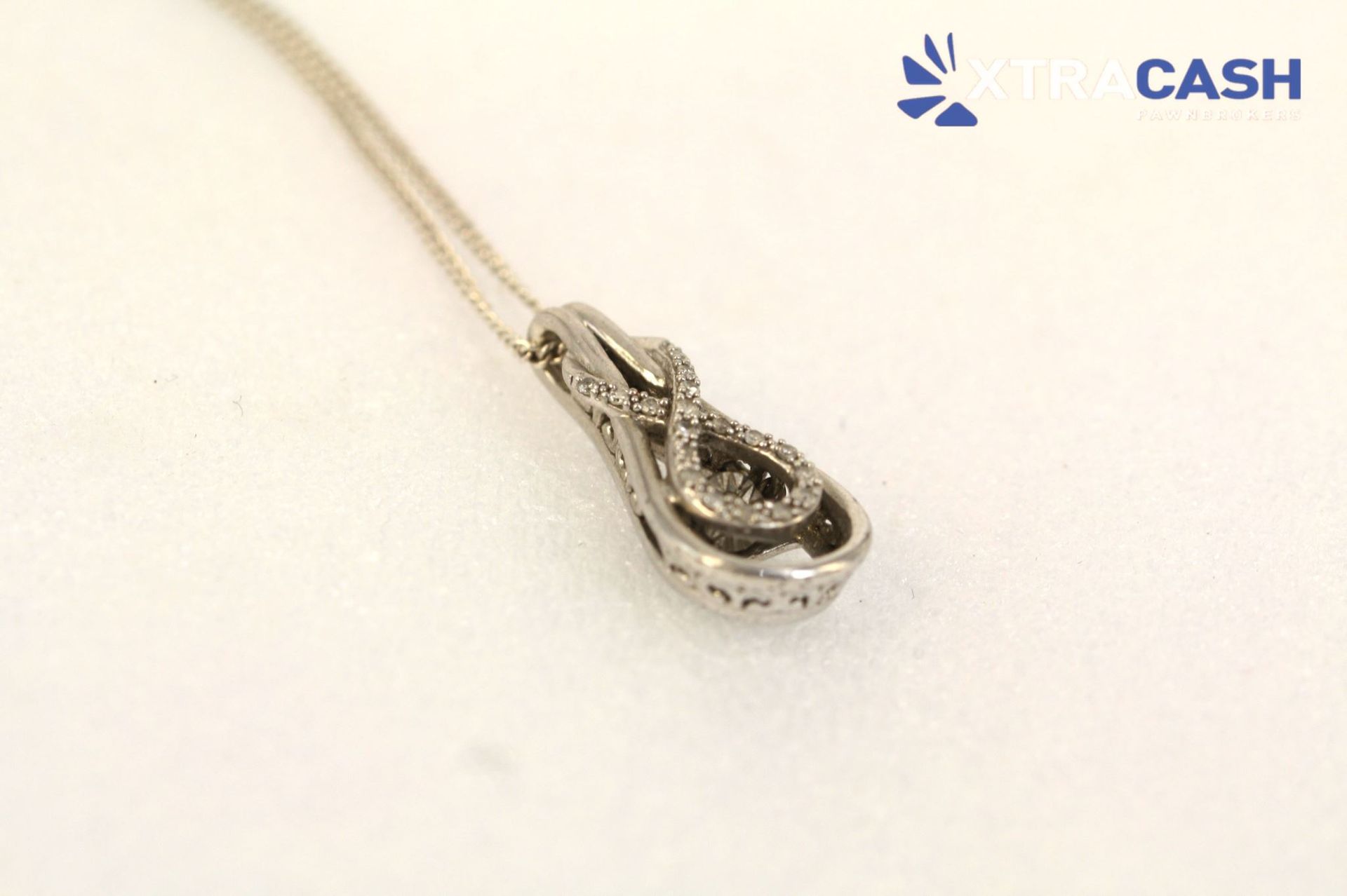 Silver teardrop pendant on a chain against a white background