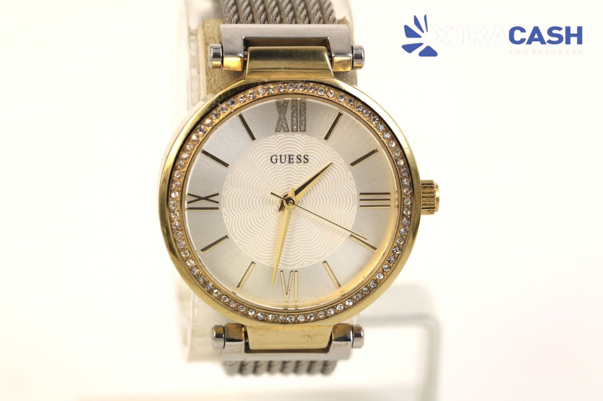 Gold-tone wristwatch with crystal-studded bezel on a display stand