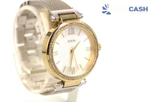 Gold-tone wristwatch with crystal-studded bezel on a display stand