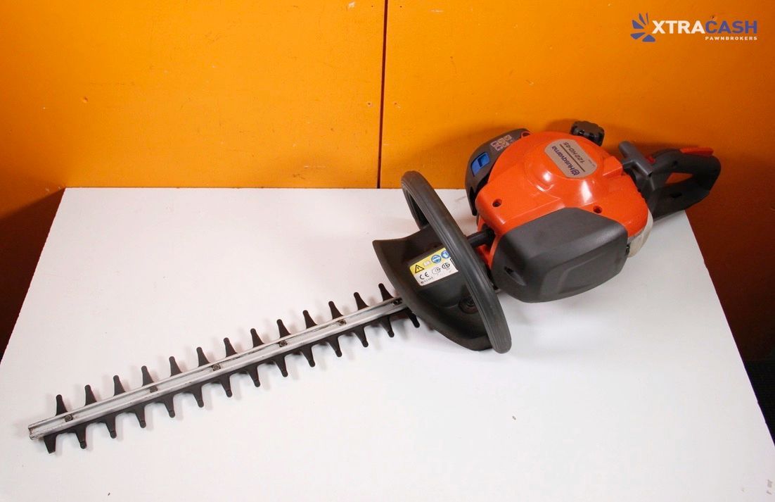 Orange and black hedge trimmer on a white surface against an orange background