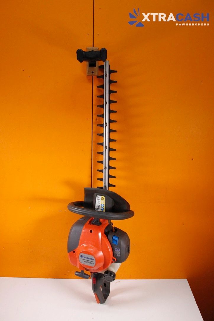 Orange and black hedge trimmer on a white surface against an orange background