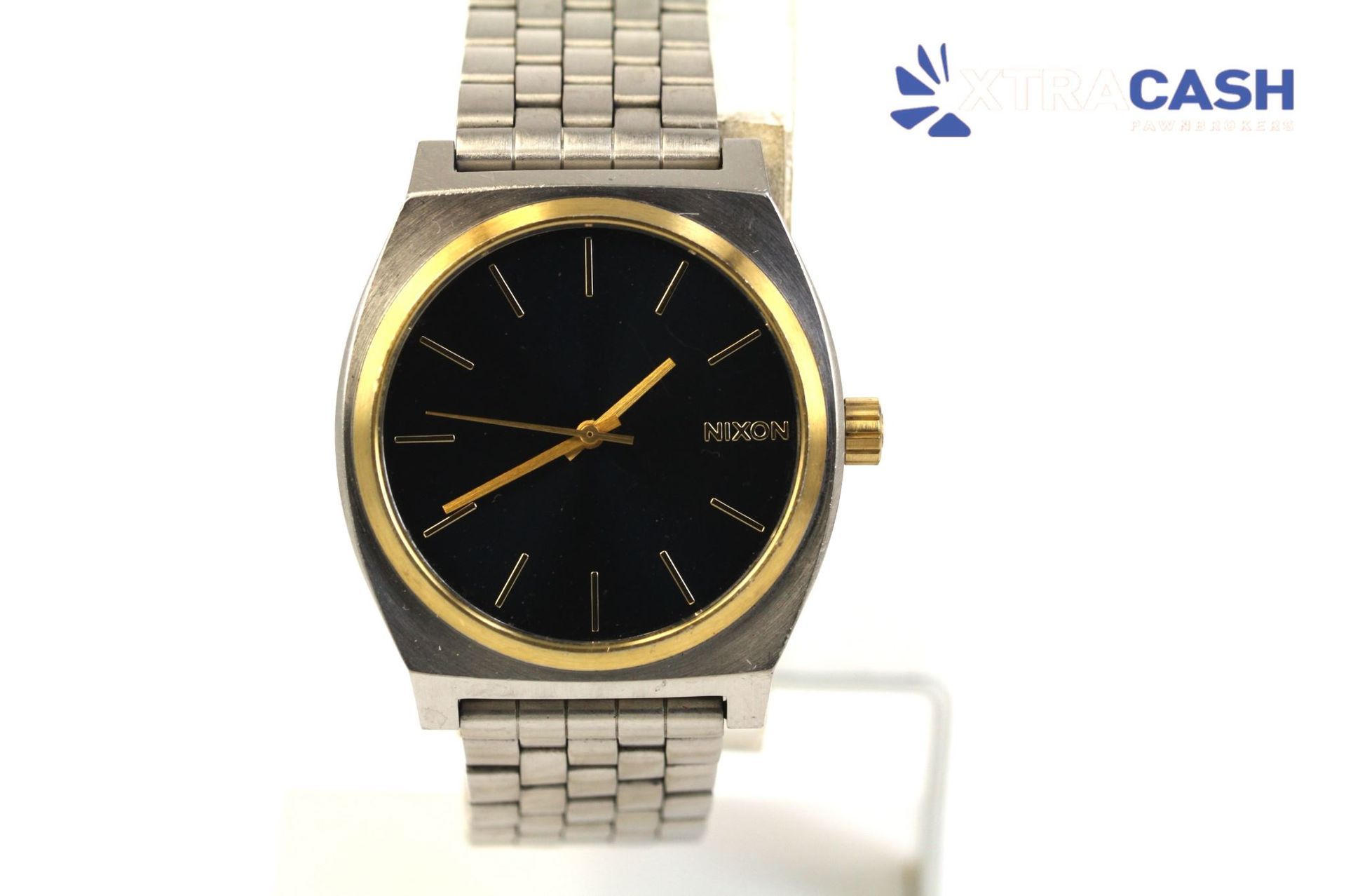 Silver and gold wristwatch with a black dial on a display stand