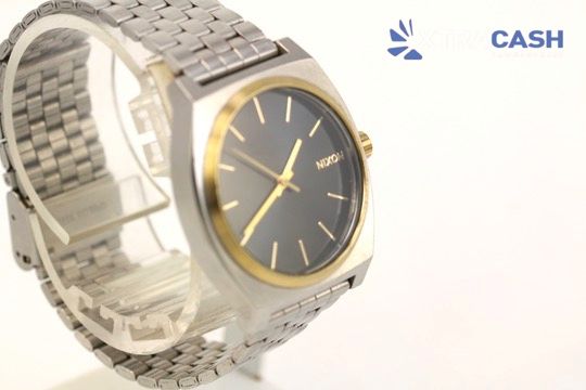 Silver and gold wristwatch with a black dial on a display stand