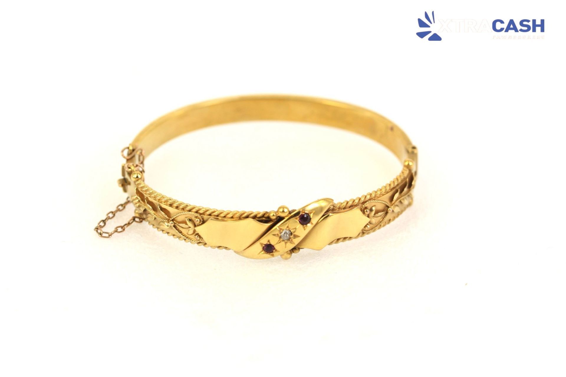 Gold bangle bracelet with engraved floral details on a white background