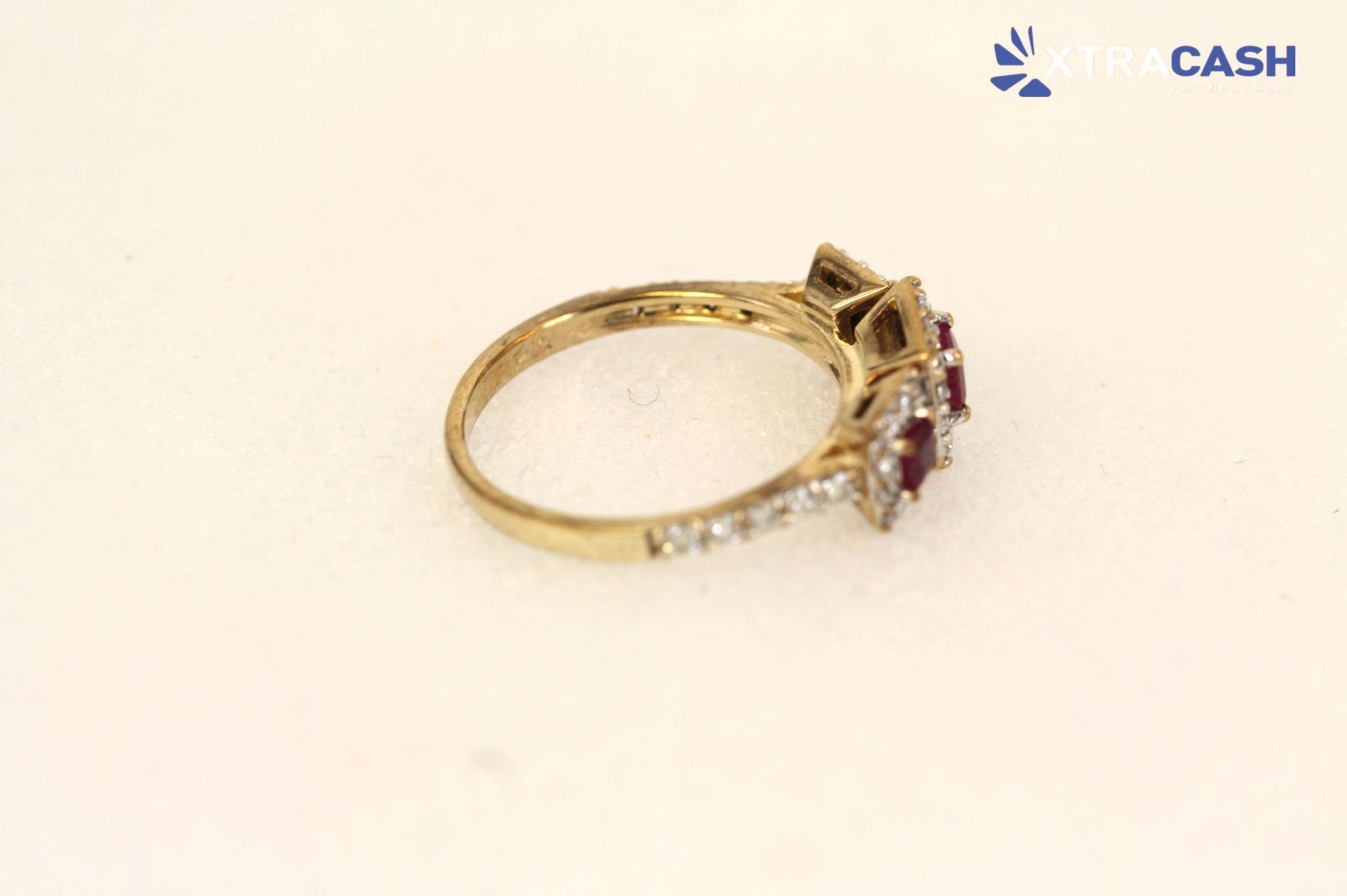 Gold ring with three red gemstones and small clear stones on a white background