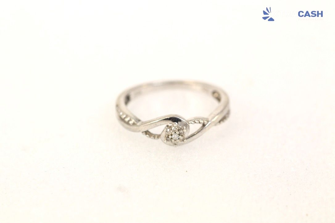 Silver ring with a small central gemstone on a white background