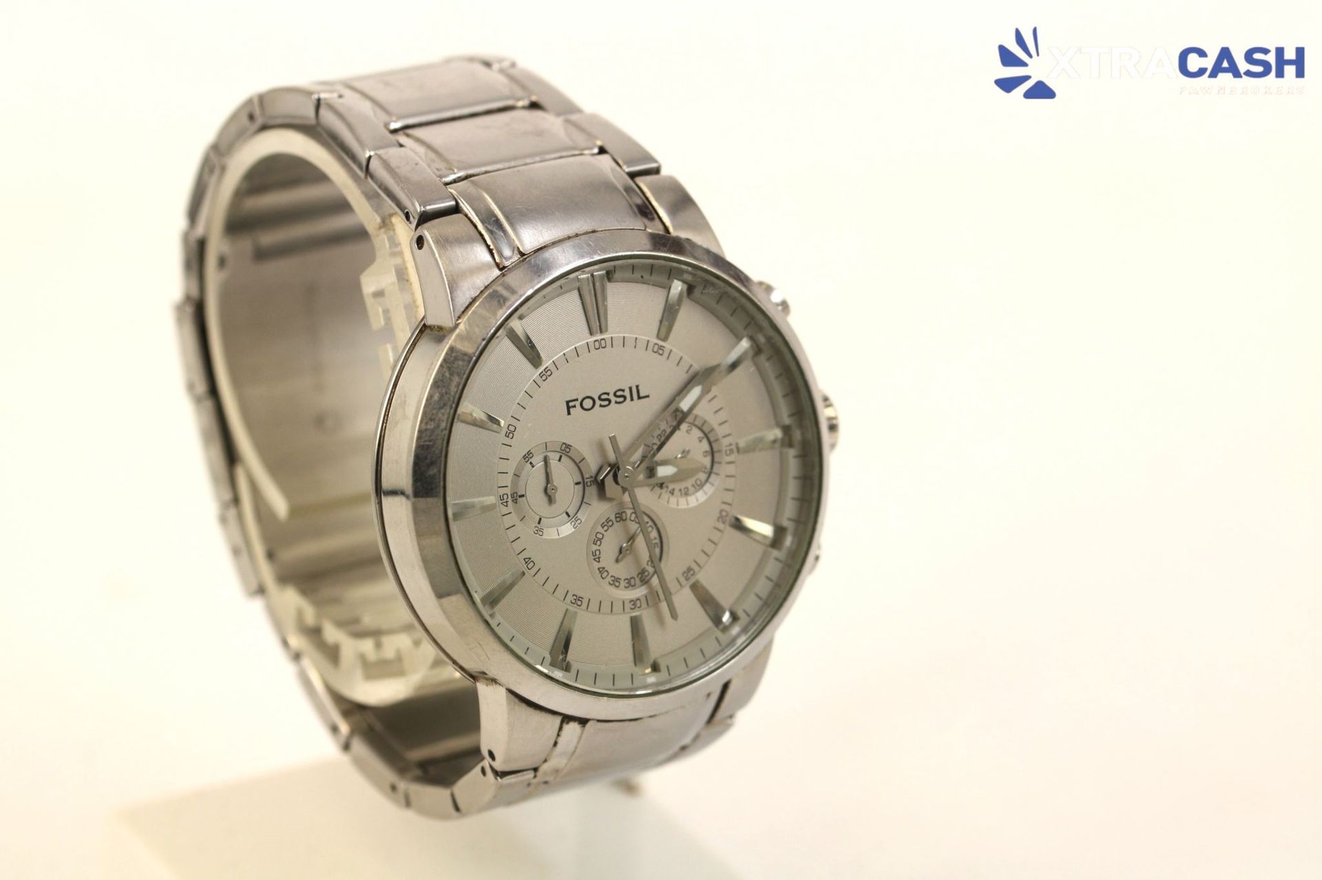 Fossil silver analog wristwatch with black markers and three subdials on a white background