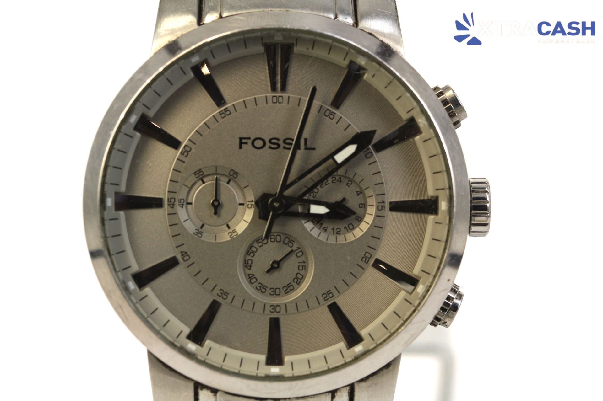 Fossil silver analog wristwatch with black markers and three subdials on a white background