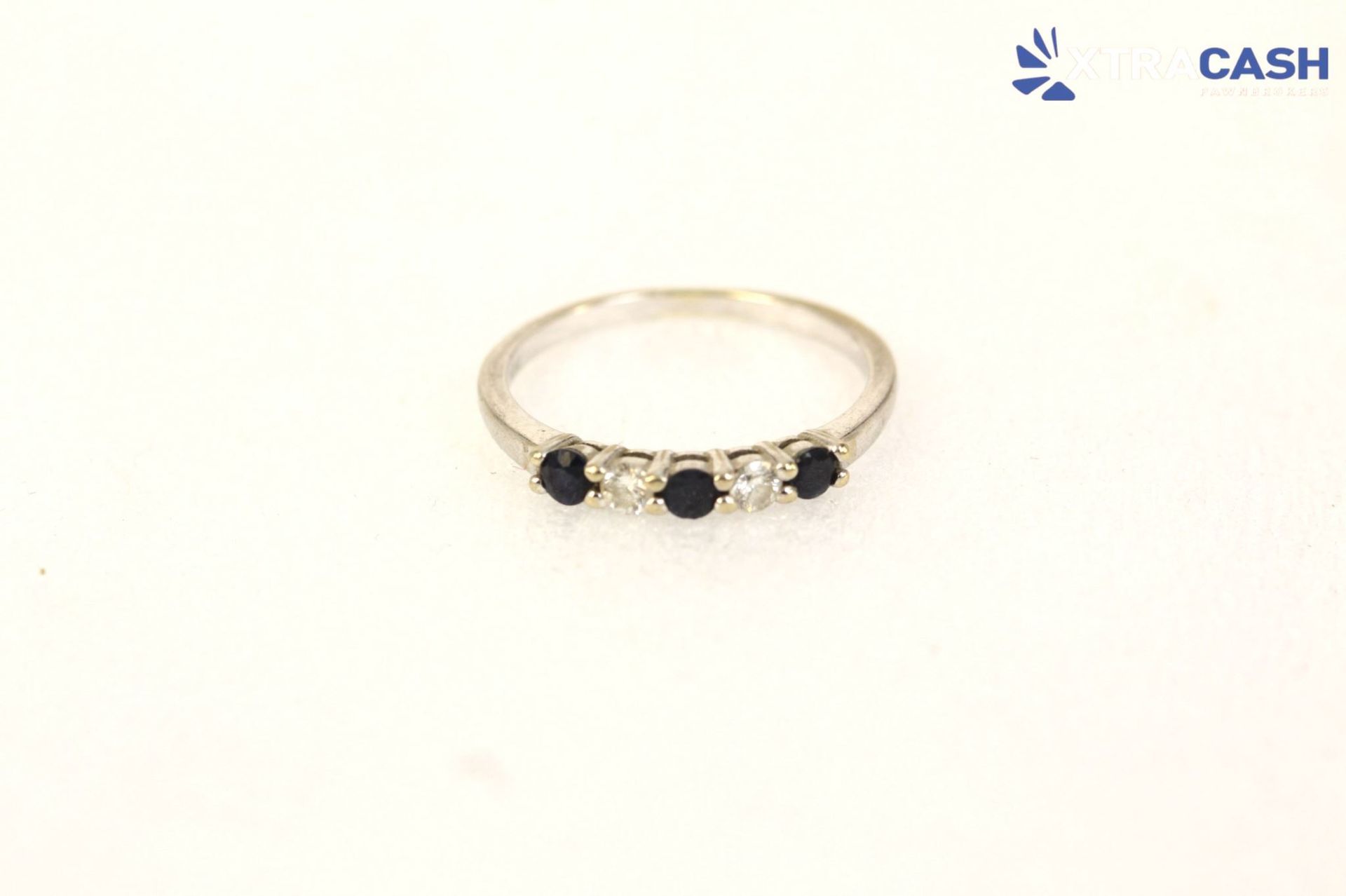 Gold ring with three dark stones on a white background