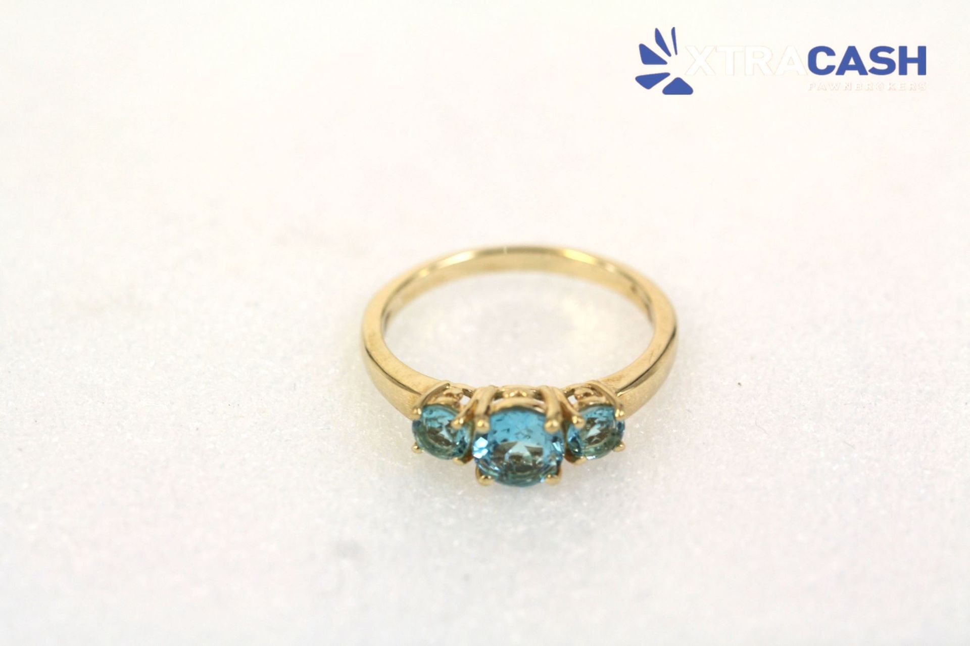 Gold ring with three blue gemstones on a white background