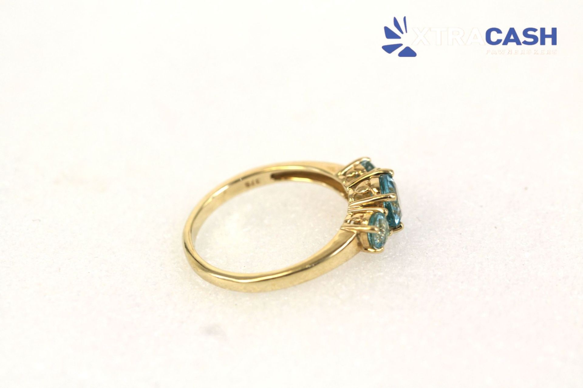 Gold ring with three blue gemstones on a white background