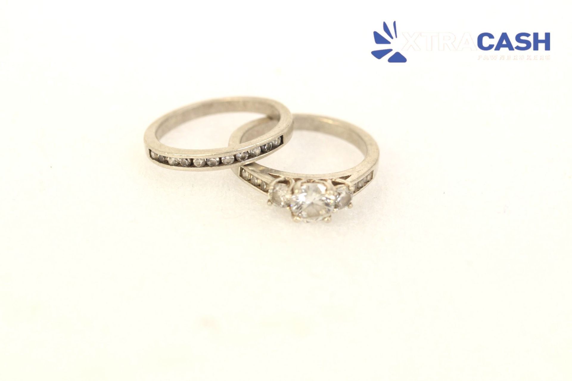 Two silver rings on a white background, one with a central clear gemstone.