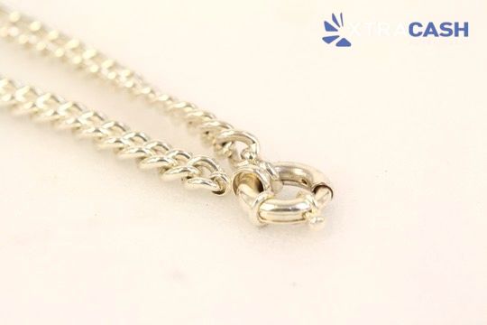 Silver chain bracelet draped over a black cylindrical rod on a light background