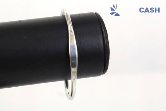 Silver open cuff bracelet with two round ends on a light background