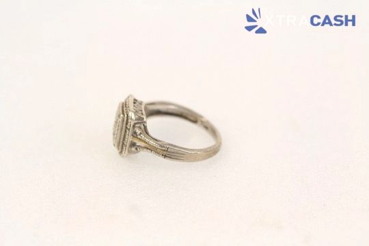 Gold ring with rectangular diamond-like center on a white background, labeled “CASH” in the top right.