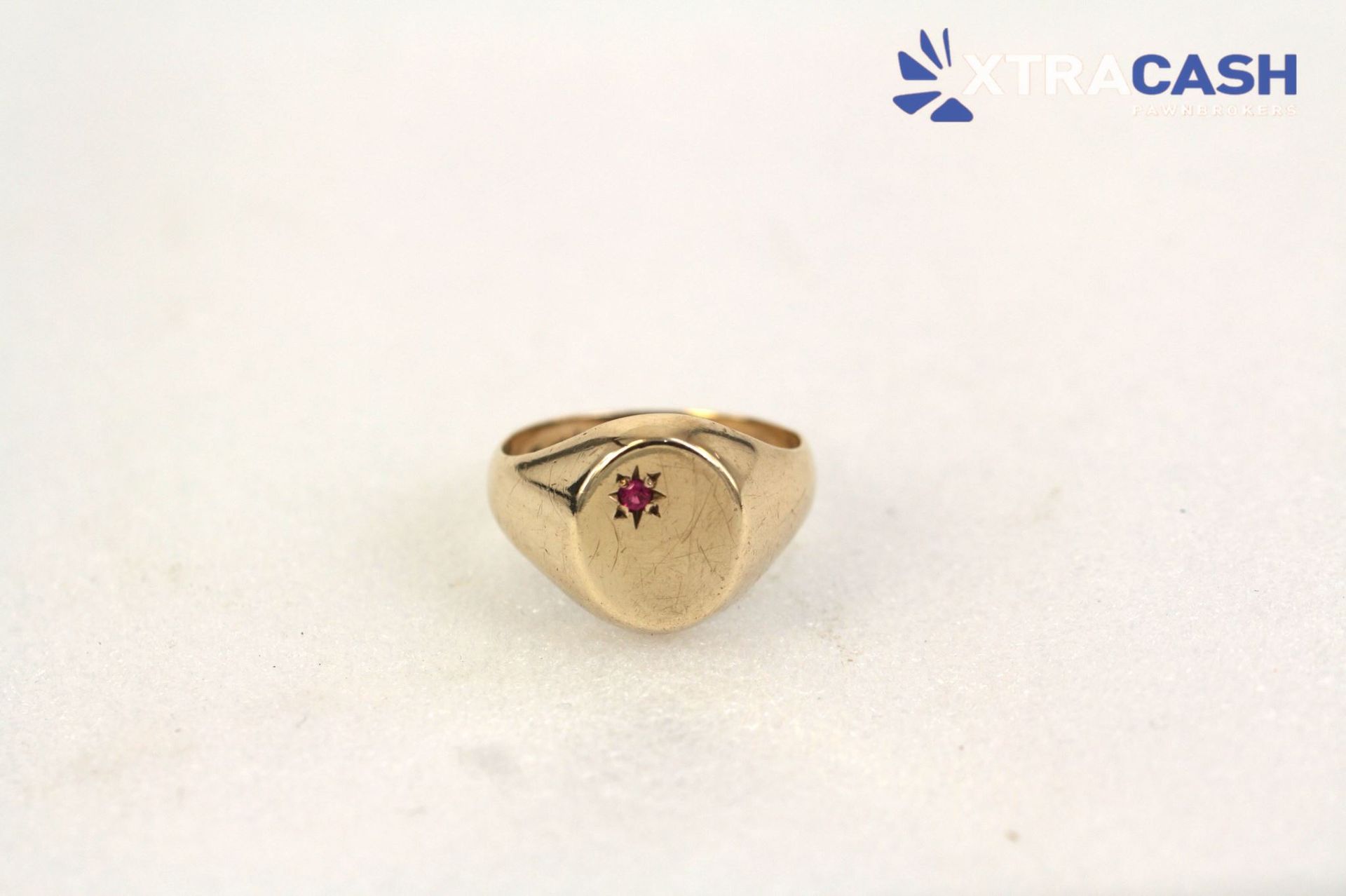 Black ring with a red stone displayed in an open black jewelry box on a white background