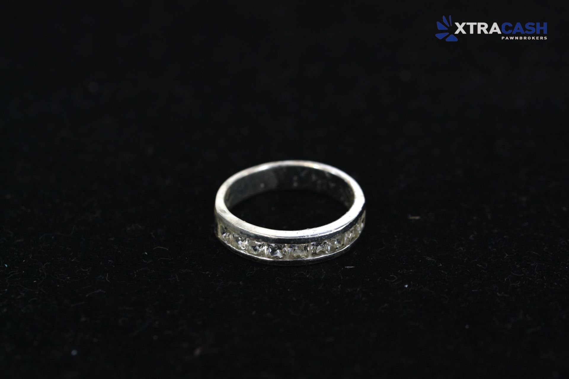 Silver diamond-studded ring on a black background