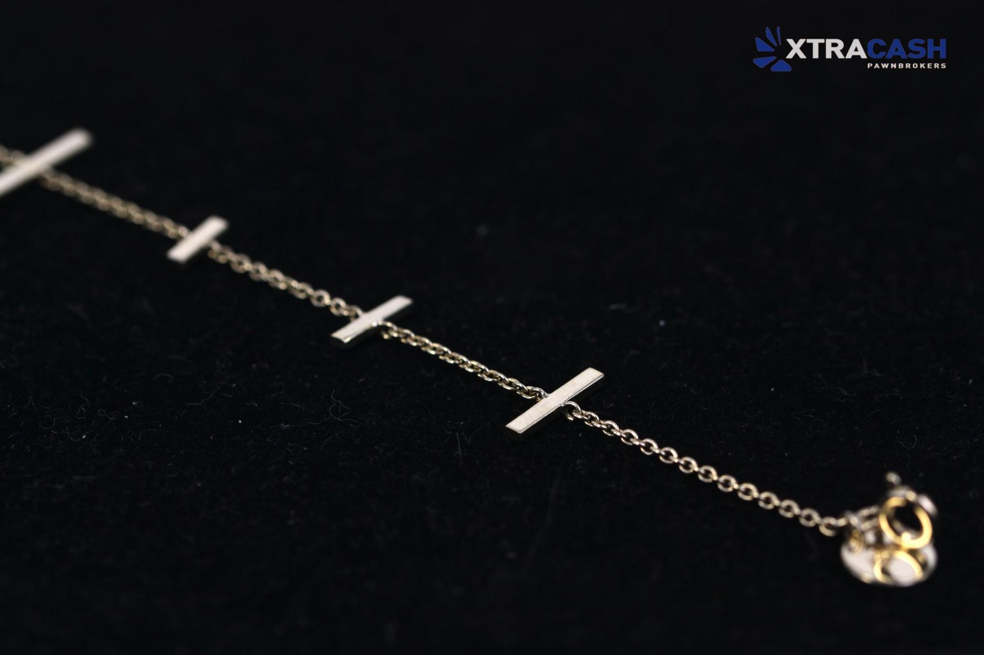 Delicate gold chain bracelet with bar accents on a dark background