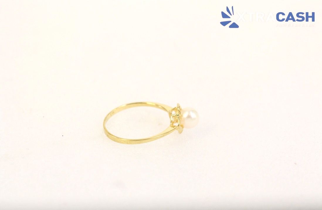 Gold ring with a pearl flower design on a white background