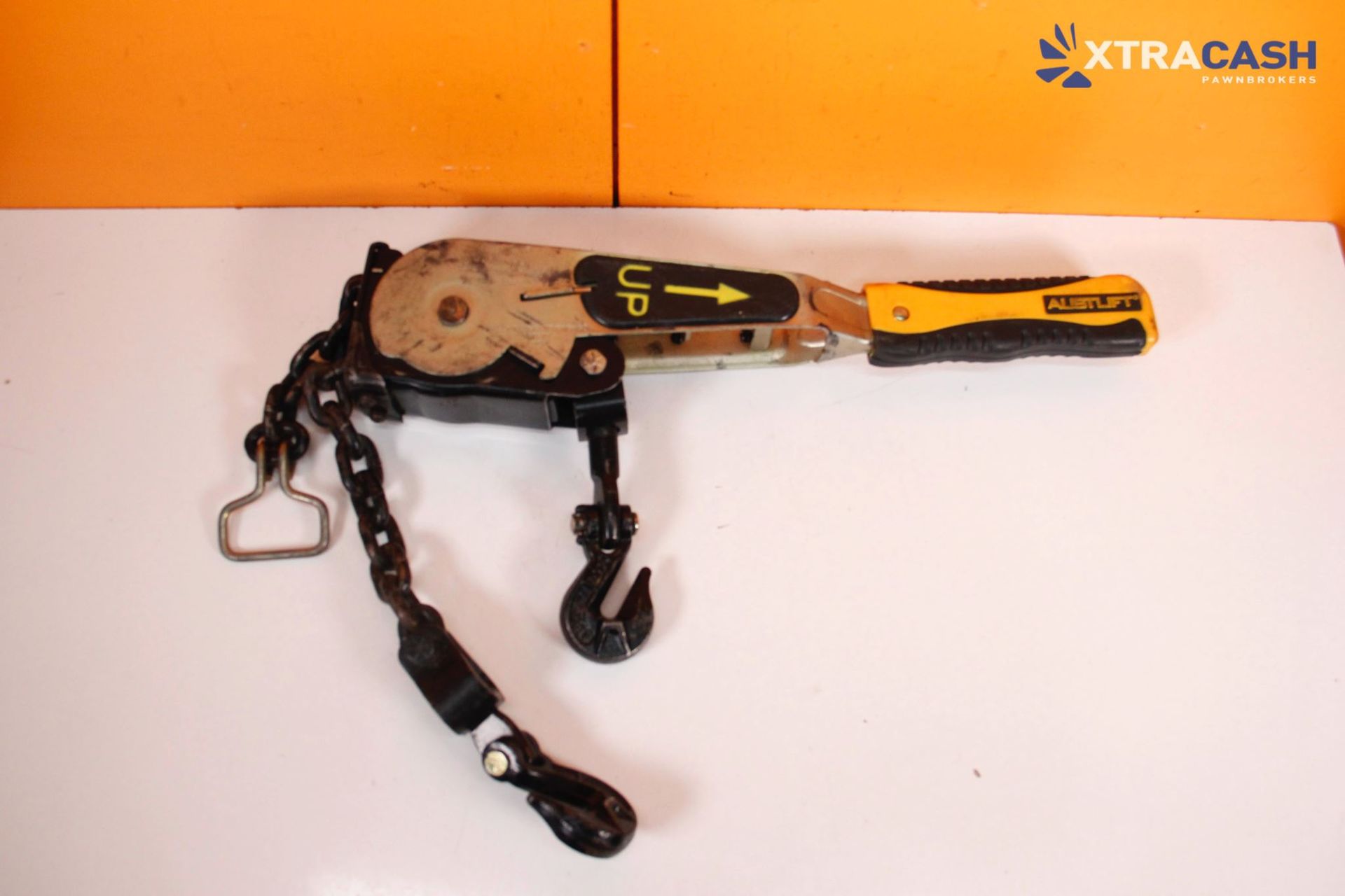 Black and yellow handheld power tool with attached chain on a white surface