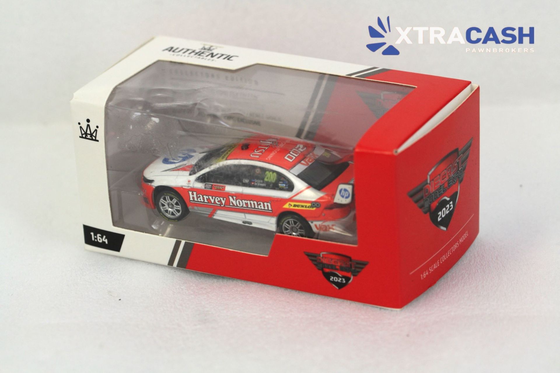 Red and white racing toy car in a clear display box with XTRACASH branding