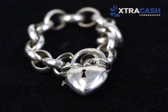 Silver chain necklace with a shiny heart-shaped pendant on a black background