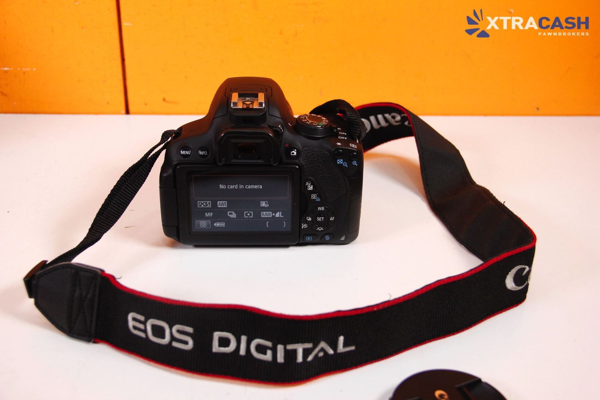 Black camera bag, DSLR camera, and battery charger on a white surface against an orange background.
