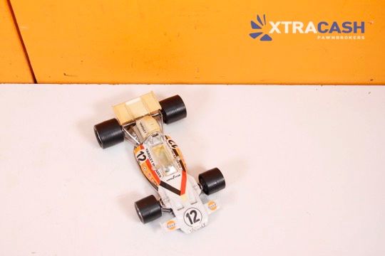 White-and-orange toy race car with number 12 on a plain white surface against an orange background.