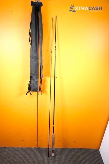 Golf club standing upright on a black floor against a bright orange wall.