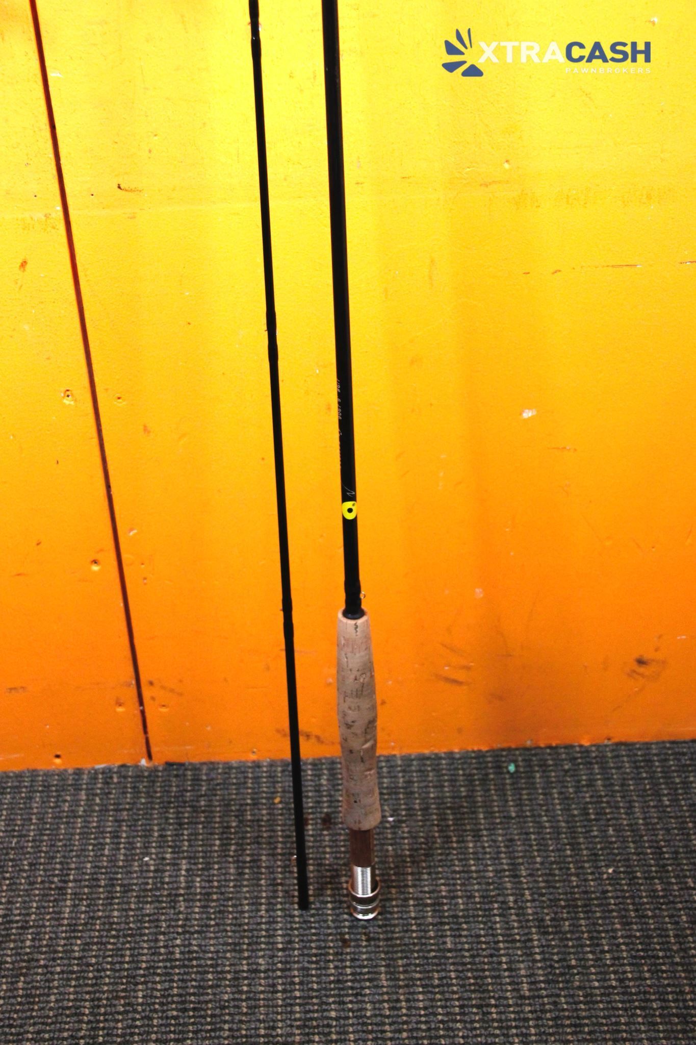 Golf club standing upright on a black floor against a bright orange wall.