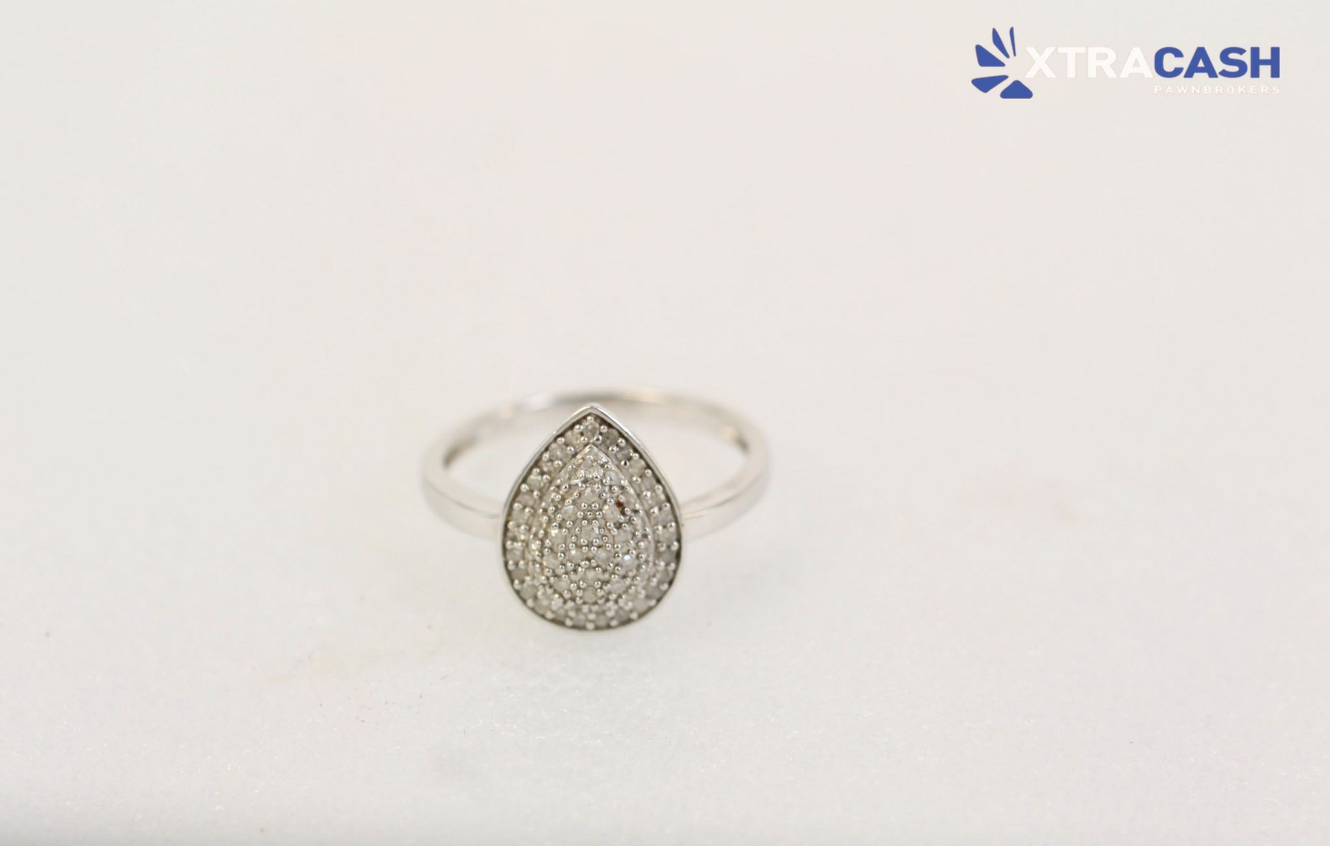 Silver teardrop-shaped ring with a sparkling pavé setting on a white background