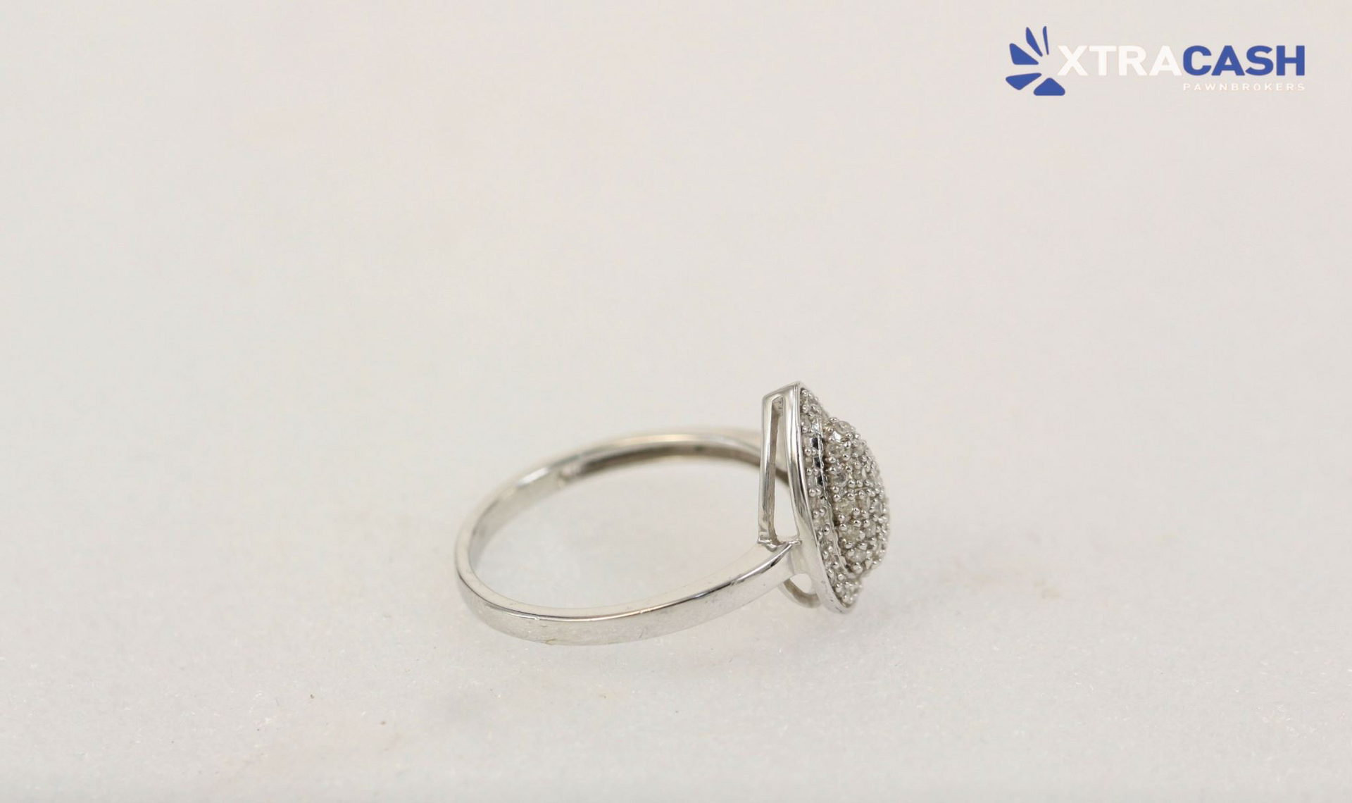 Silver teardrop-shaped ring with a sparkling pavé setting on a white background