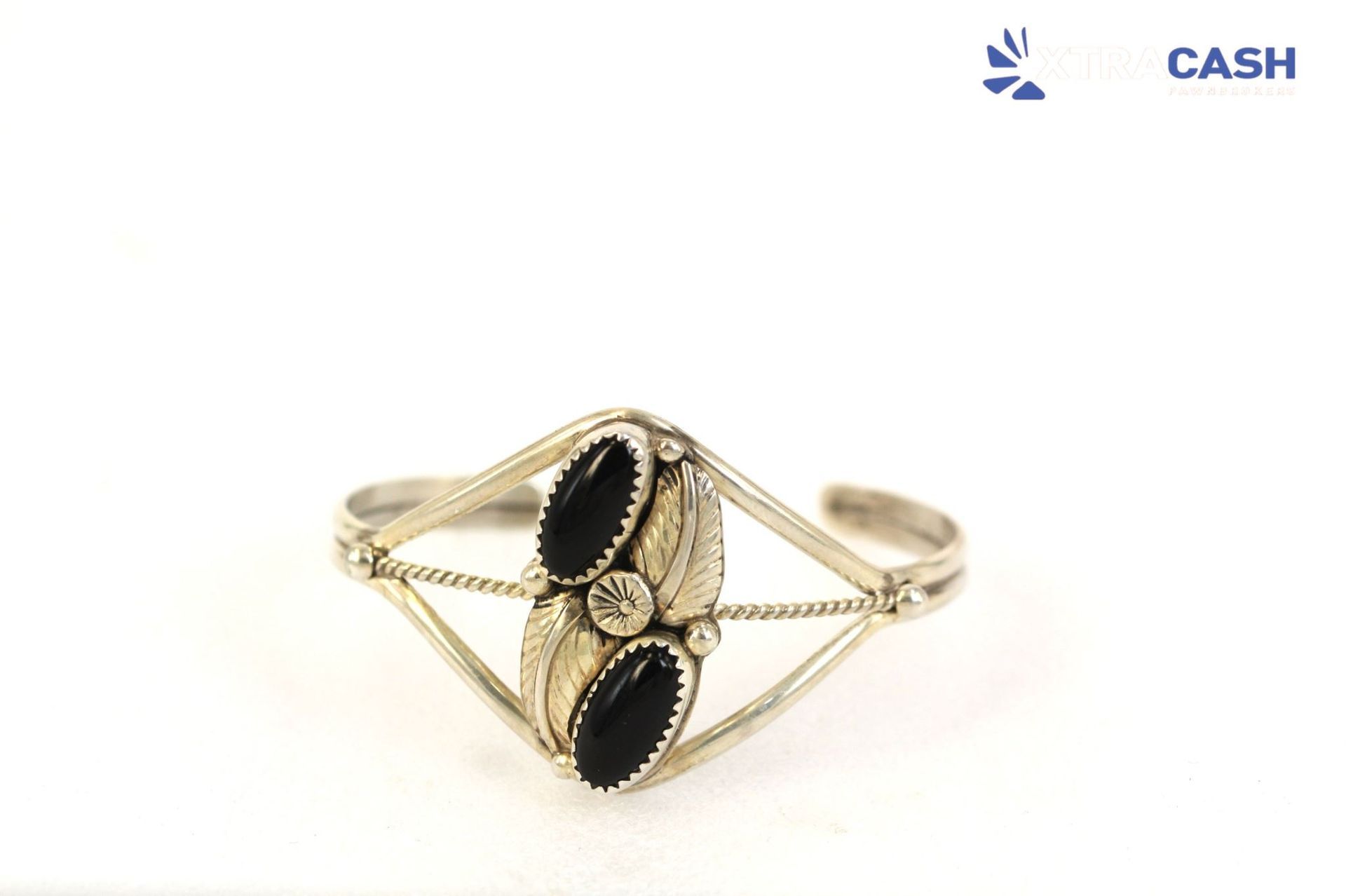 Gold ring with black oval stones and a geometric wire design on a white background