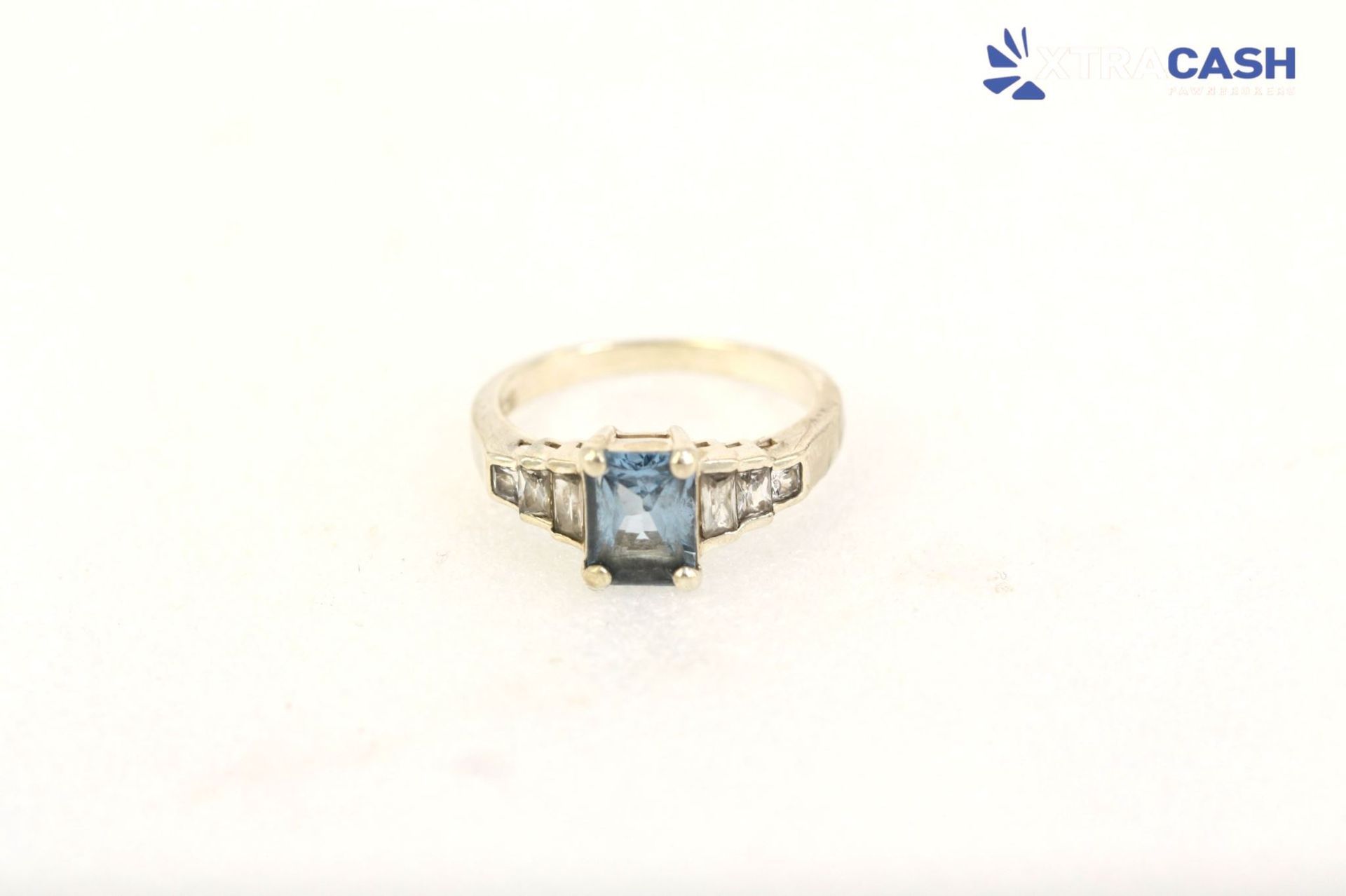 Gold ring with a square blue gemstone on a white background