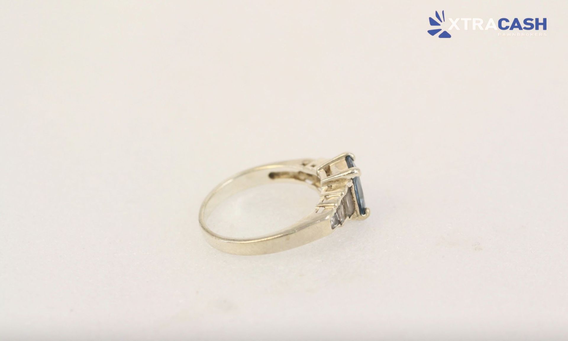 Gold ring with a square blue gemstone on a white background