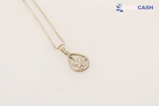 Gold necklace with a teardrop pendant on a light background