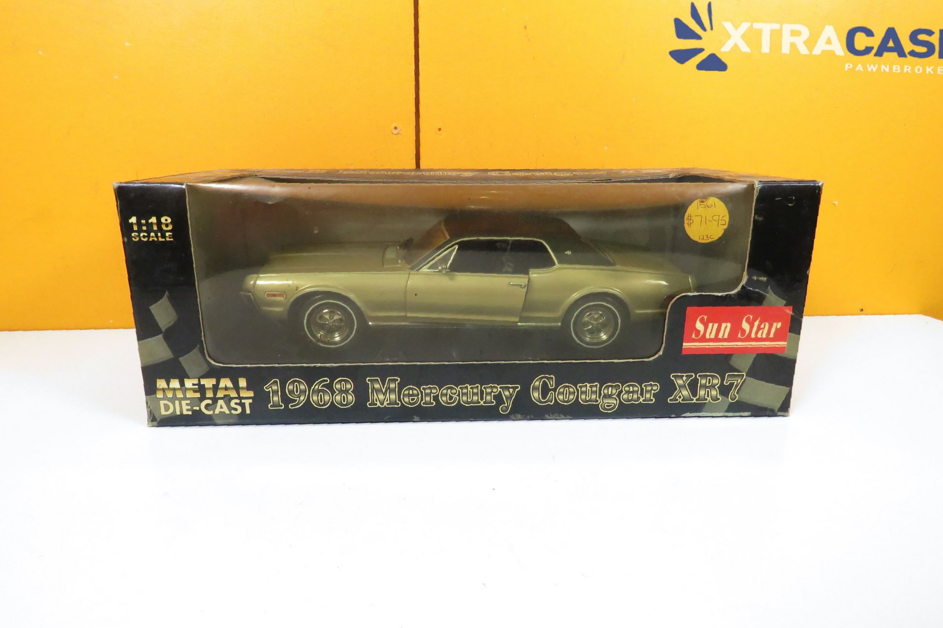 Toy black classic car in a display box on a yellow and white surface.
