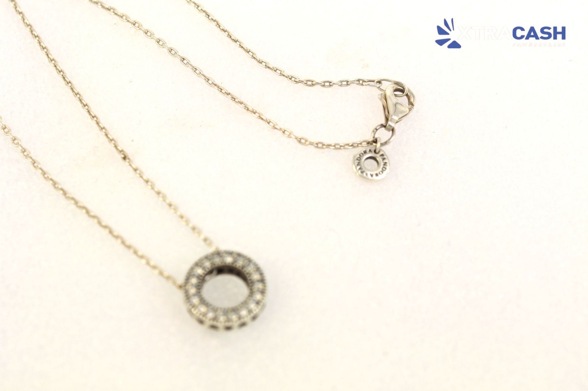 Gold necklace with a circular pendant on a white background